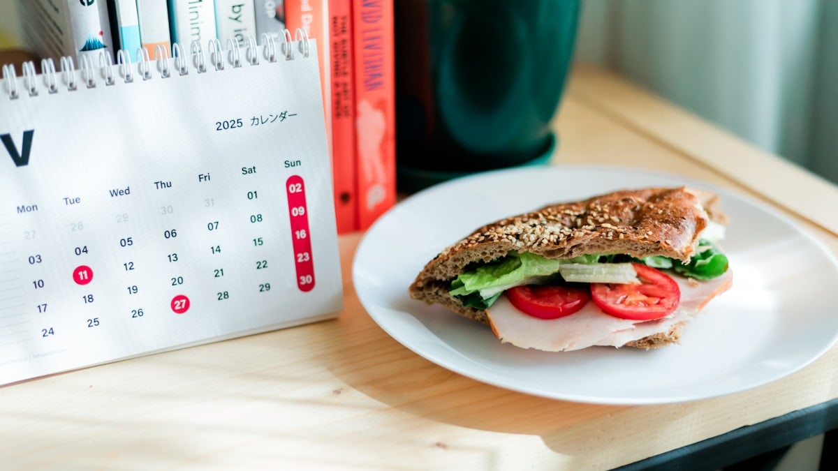 Sandwich with tomato and lettuce on a desk.